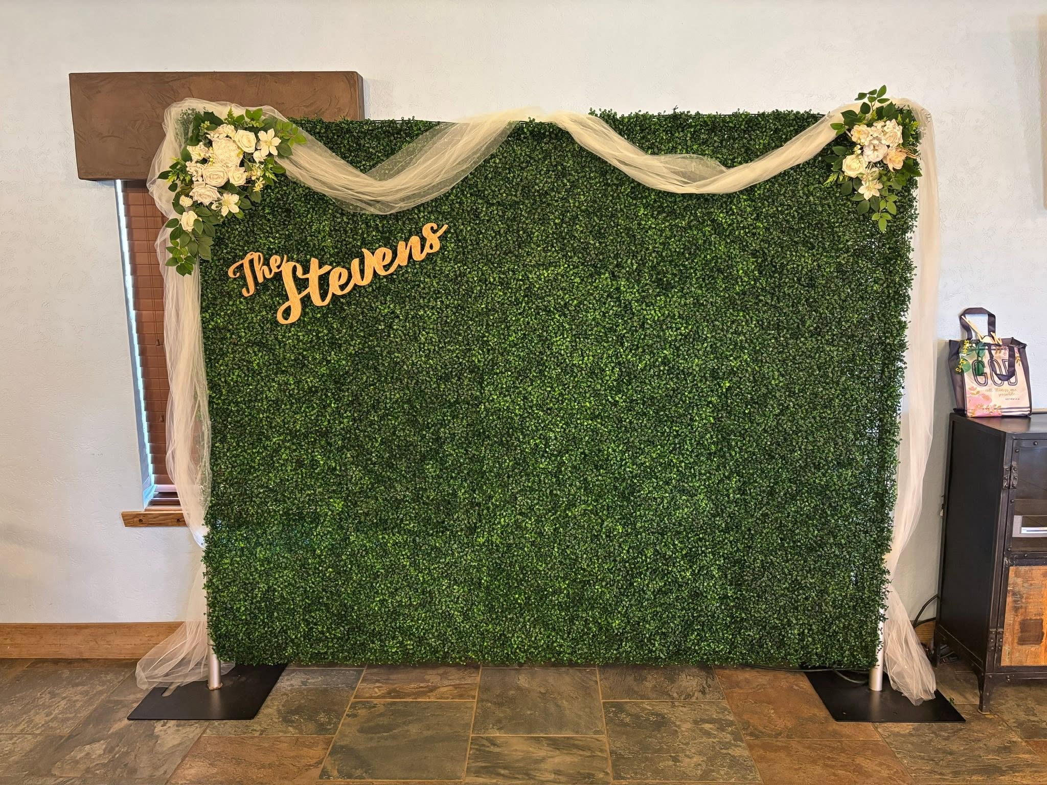 Greenery backdrop wall with ivory tulle draping and floral corner pieces — Stevens Wedding